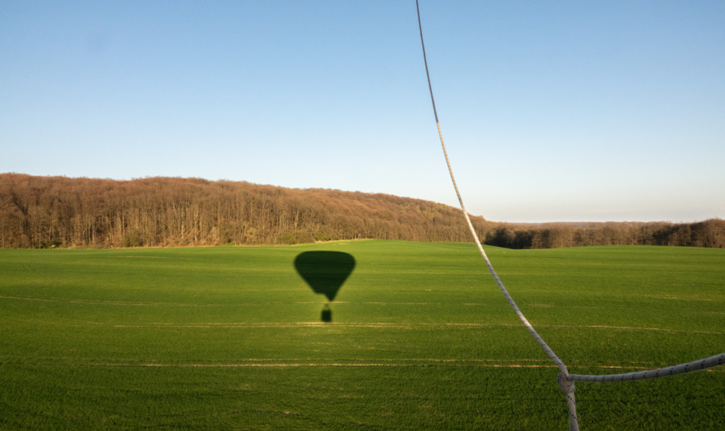 Balon lecący nad polem i jego cień